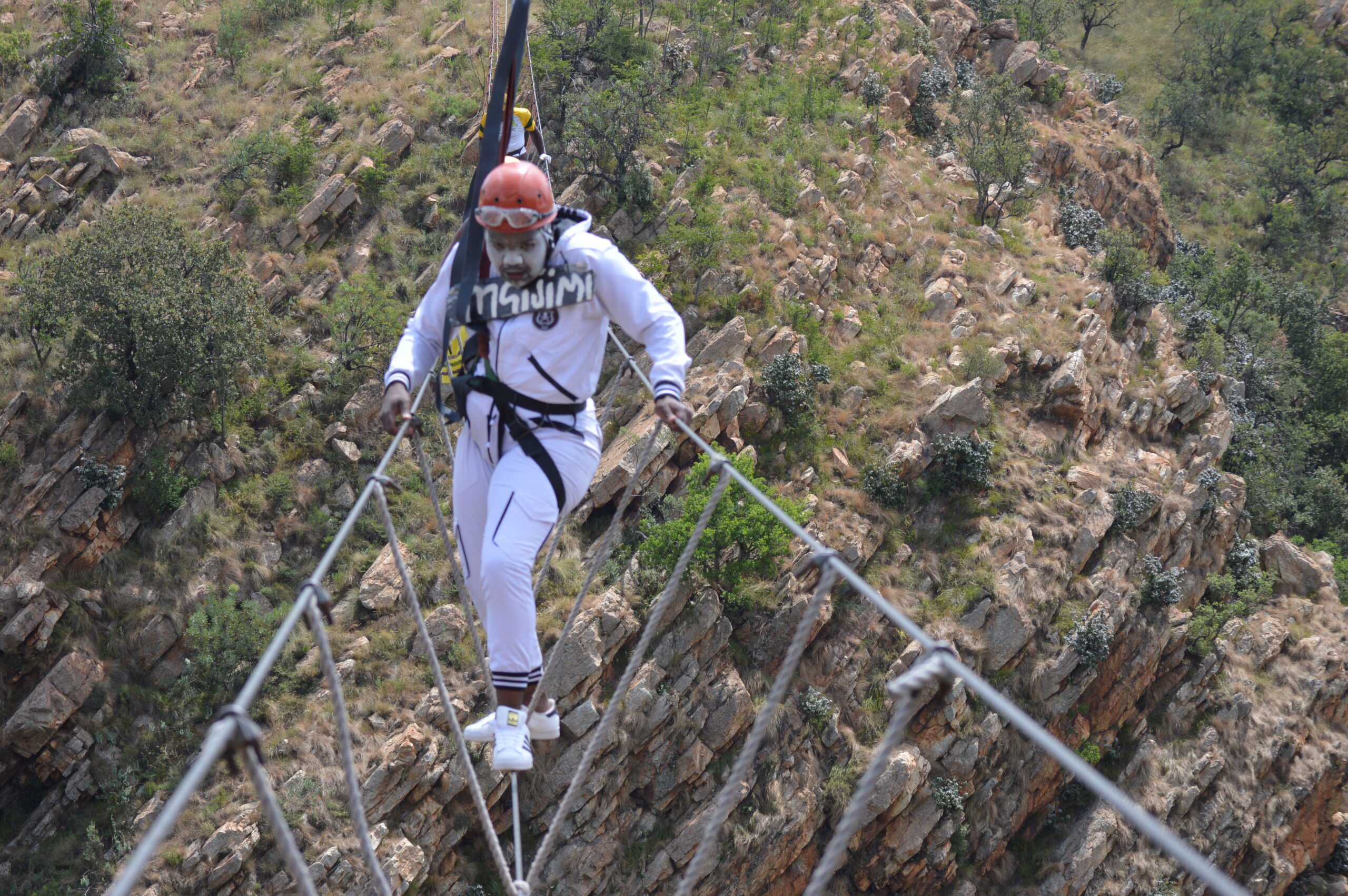 Participant crossing the Adventure Burma Bridge during an outdoor team building and leadership challenge.